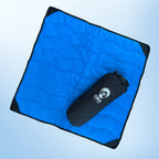Blue quilted blanket with a black compression bag on a light blue background
